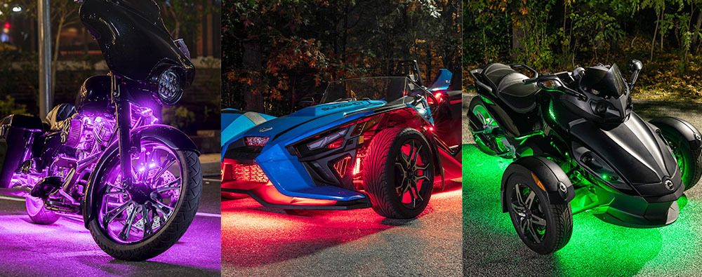 A touring motorcycle, Polaris Slingshot and Can-Am Spyder lit up with purple, red and green LED accent lighting